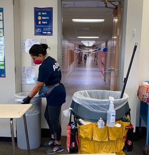 MAINTAINING COVID PRECAUTIONS: ABM worker Araseli works to clean the school after hours. The custodians must go up and down each row of desks, spraying and wiping them down, in addition to their usual jobs.