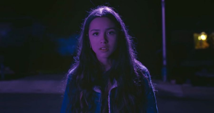 A scene from the Drivers License music video, which features 17-year-old Olivia Rodrigo walking and driving through the suburbs. Rodrigos debut single Drivers License is breaking the charts.