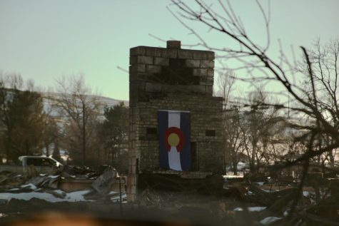 A Colorado flag hangs on a chimney in Old Town Superior. The Old Town neighborhood was among a few burned entirely to the ground in Superior and Louisville, Colorado, in the Marshall Fire, which swept Boulder County Dec. 30.