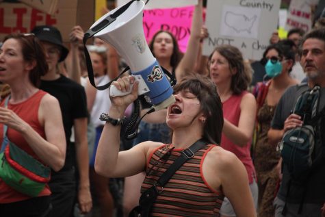 A protester shouts call-and-response chants into a megaphone near the Colorado Capitol on Monday. Organizers stood on slow-moving vehicles or walked with the crowd to keep everyone on pace and chanting in unison.