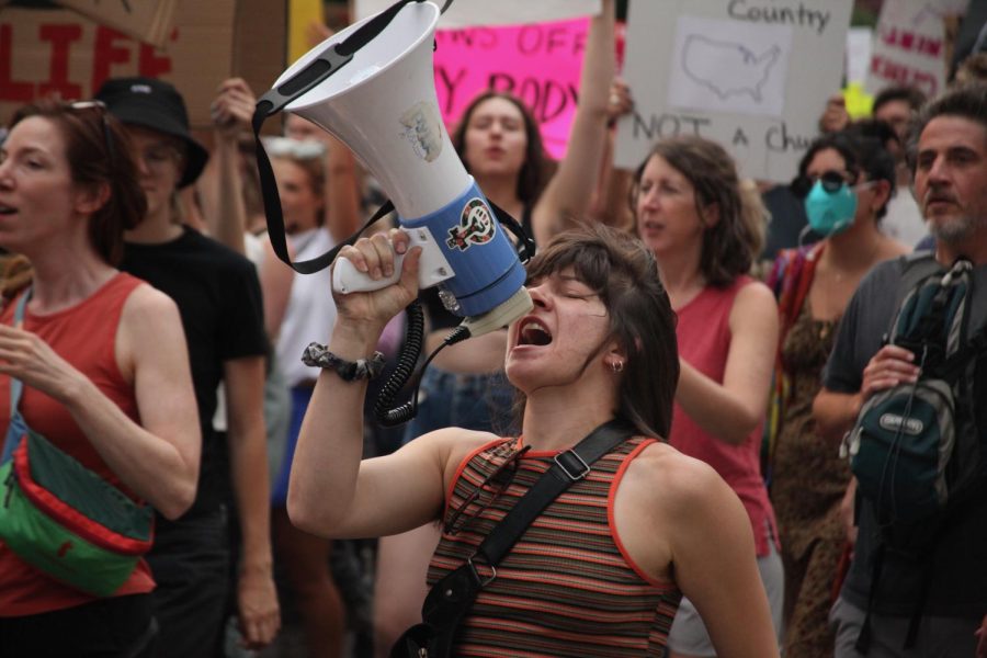 A protester shouts call-and-response chants into a megaphone near the Colorado Capitol on Monday. Organizers stood on slow-moving vehicles or walked with the crowd to keep everyone on pace and chanting in unison.