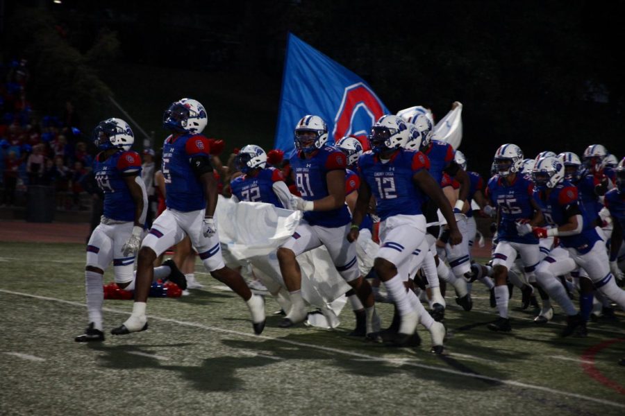 The+football+team+breaks+through+the+paper+banner+held+by+the+cheer+team+right+before+the+game.+The+banners+are+made+by+Student+Senate+the+day+before.+The+football+team+won+their+home+opener+game+versus+Chatfield+28-5.