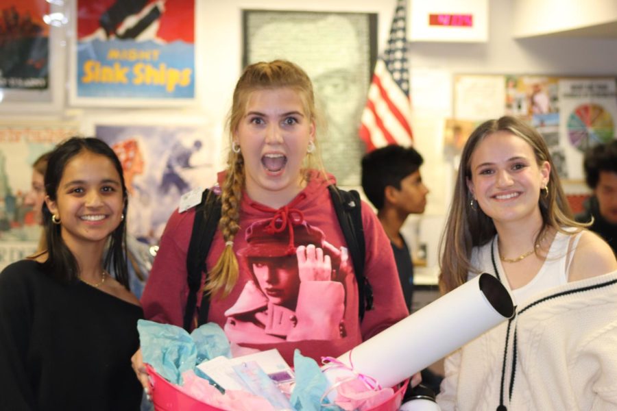 Taylor Swift Club co-founders and Creek seniors Gauri Thaliyil (left) and Julia Gralla (right) with sophomore Norah Armstrong (middle) after Armstrong won the club’s Taylor Swift gift basket raffle at the club’s kickoff. (Jude Gorden)