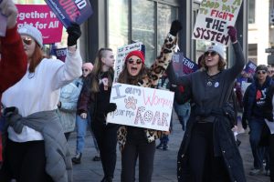 A protester chants carries a sign saying I am woman, hear me roar during the 2023 Womens March on the 16th Street Mall. The line, originally from the song I Am Woman by Helen Reddy, is commonly used in abortion rights protests.