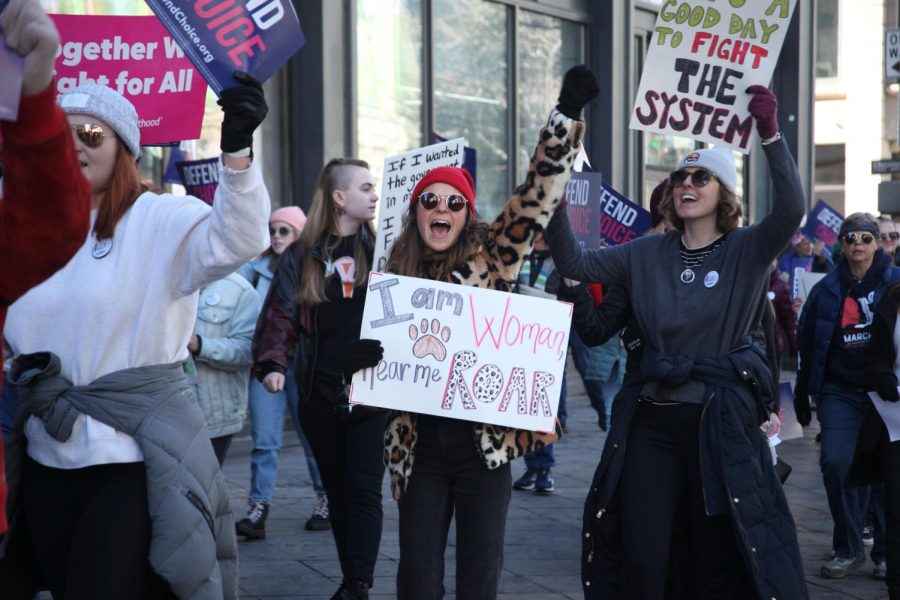 A+protester+chants+carries+a+sign+saying+I+am+woman%2C+hear+me+roar+during+the+2023+Womens+March+on+the+16th+Street+Mall.+The+line%2C+originally+from+the+song+I+Am+Woman+by+Helen+Reddy%2C+is+commonly+used+in+abortion+rights+protests.