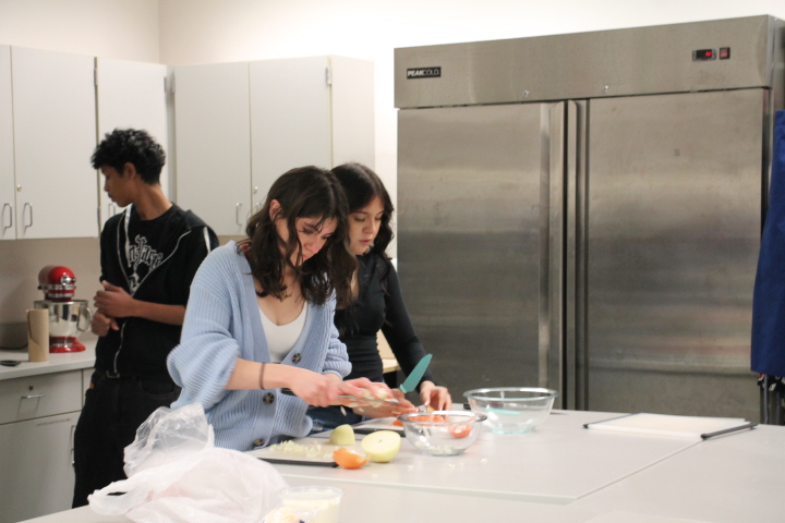  Freshman Alexa Casillas Martin and sophomore Jocelyn Hernandez cut onions and peppers in the culinary room while in Spanish teacher Wilmer Barrera’s Native Speaker Spanish class. Barrera wants his students to learn about Spanish culture through daily life experiences such as cooking so he incorporates cooking into his classroom teaching. “I graduate[d] from college and I love being in front of the classroom,” Barrera said.