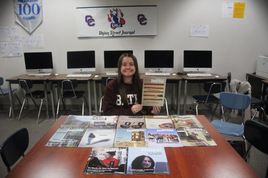 Graduating Editor-in-Chief Carly Philpott poses with all of the magazines she worked on (minus Winter 2020, which the USJ archives doesnt have) and holds up her final issue.