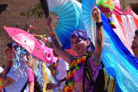 A representative of Meow Wolf, a psychedelic walk-through art experience that opened a location in Denver in September 2021, smiles at the crowd during the parade. The Denver Pride parade was on Sunday, June 25 after a weekend of other celebrations, including a 5K and small marketplace, in downtown Denver. 