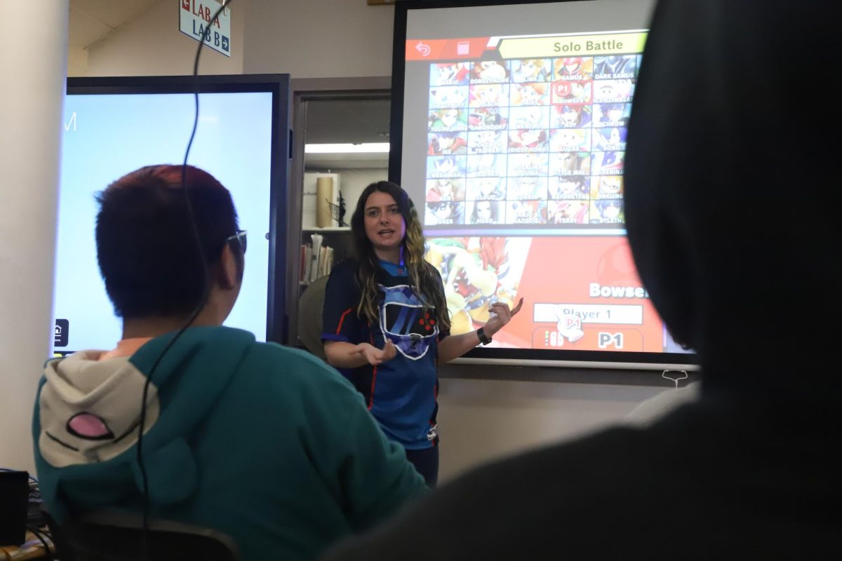 Creek eSports coach Alexandra Bak talks about "Super Smash Bros" characters before her students begin a match. Bak coaches 12 separate video game teams in her position. Students appreciate her coaching style. “I love having [Ms. Bak] as the eSports coach, she brings a lot to eSports by helping us communicate and [working on our] teamwork," senior varsity Mario Kart player Satia Baird said.