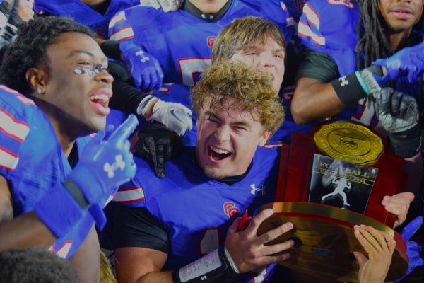 Members of the football team, alongside junior quarterback Brady Vodicka (#13), celebrate as they are handed the 5A trophy for winning the state championship. The team beat Legend high school on Dec. 7 in CSU’s Canvas Stadium with a score of 13-0.