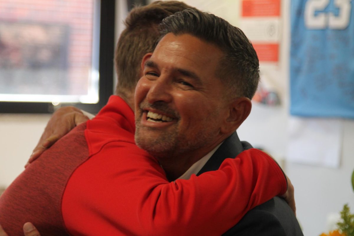 Principal Ryan Silva embraces social studies teacher David Knoeckel after presenting him with the Educator of the Year award. "Silva came in, and then I saw the flowers, and it registered," Knoeckel said. "I was like, 'No way is this happening?'"
