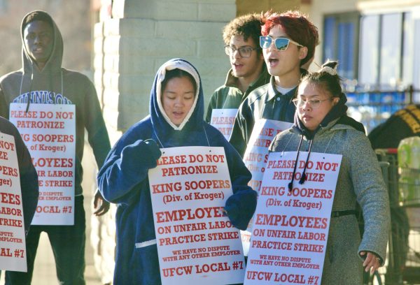 Workers yell chants, donning signs that encourage customers to not shop at the store, in front of the Belleview Square King Soopers.