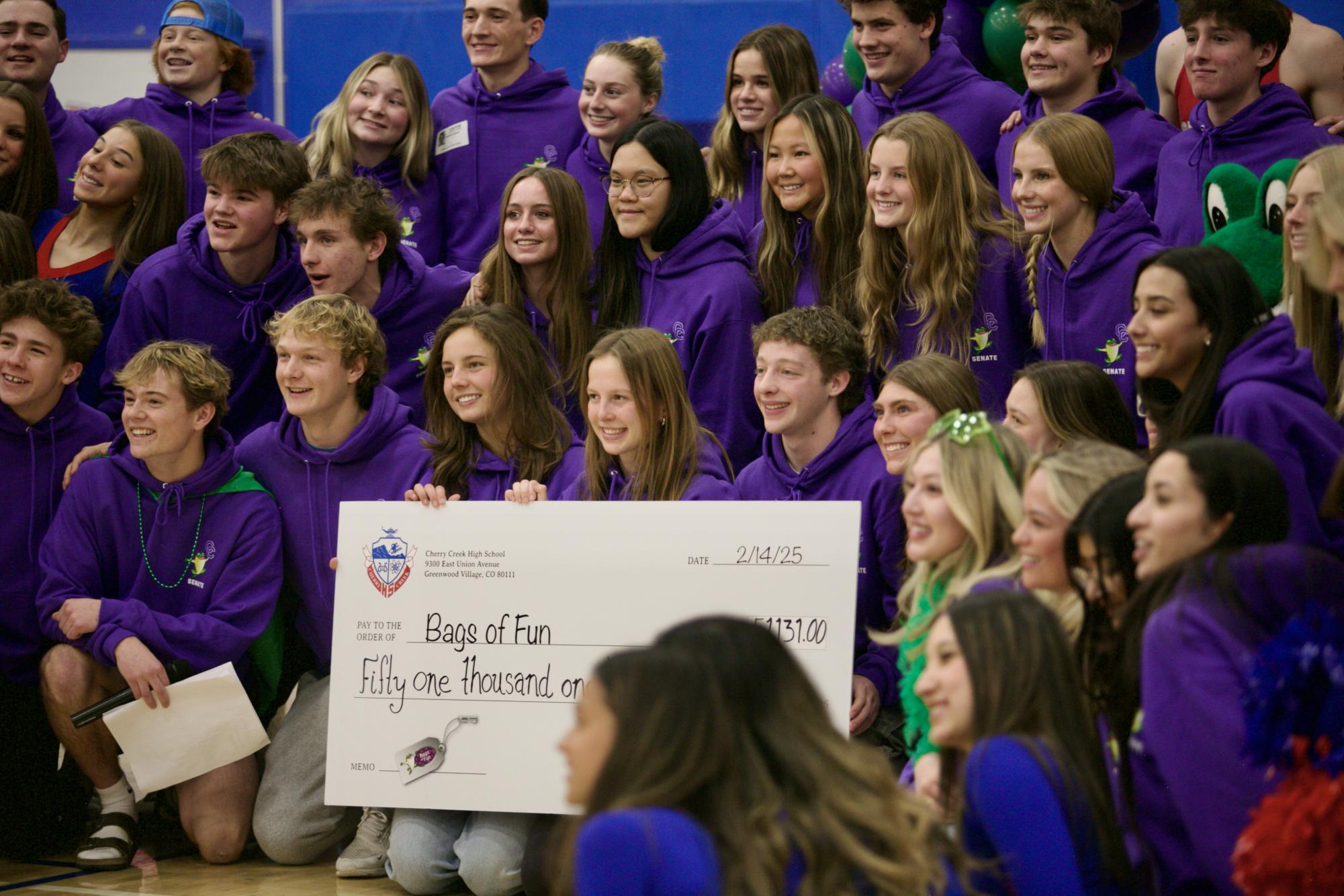 Members of Senate, assembly performers, the cheer team and the poms team group together for a photo with the final donation check after the assembly, marking the end of Power Week.