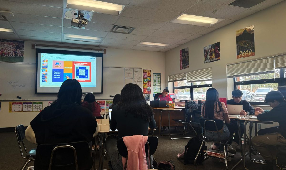 Spanish 4 Honors for Native Speakers  teacher Wilmer Barrera helps students register for an upcoming national Spanish test.