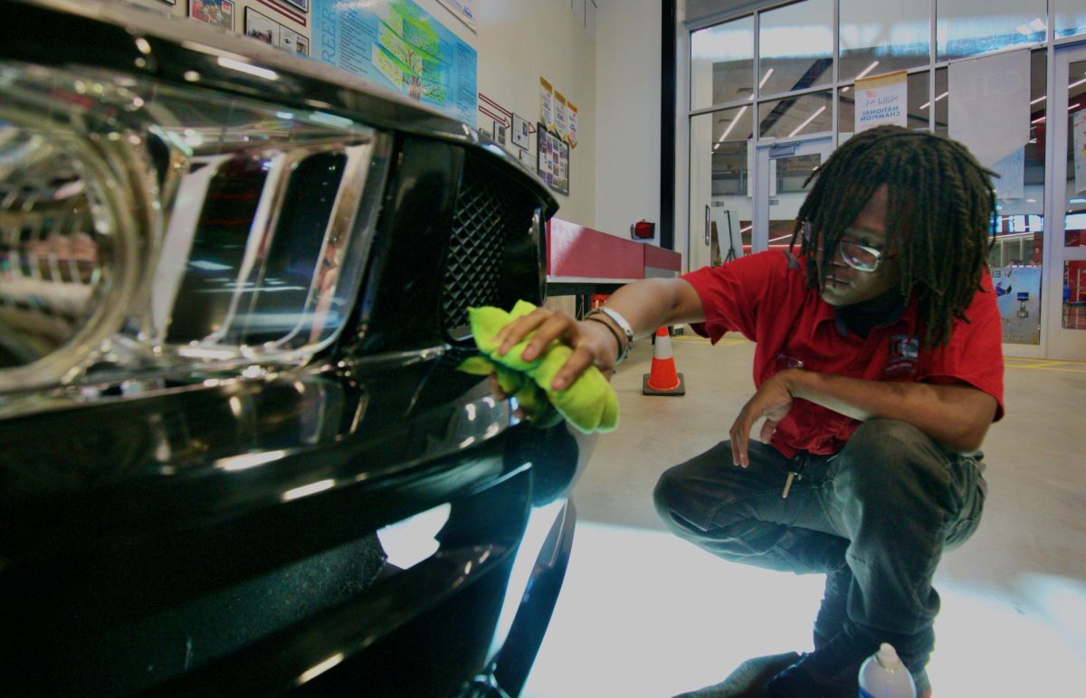 A student in one of CCIC's automotive classes cleans off a show car in their warehouse.