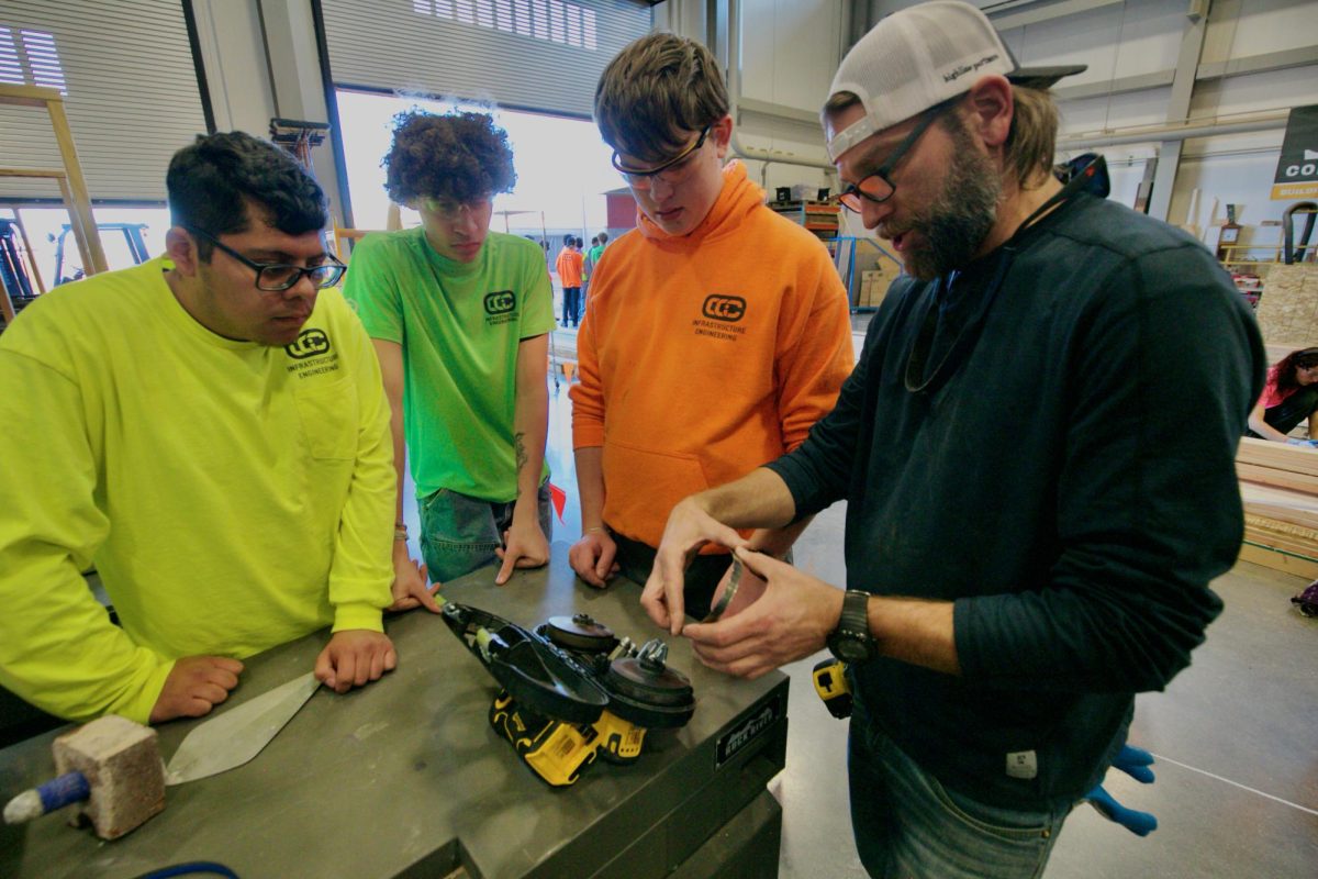 Students in a CCIC construction class practice how to use a saw in an infrastructure class. 