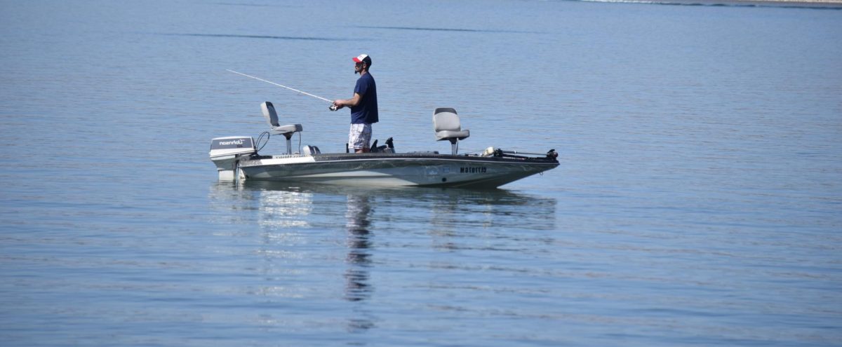 A man enjoys the reservoir, fishing from his boat.
