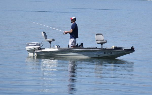 A man enjoys the reservoir, fishing from his boat.
