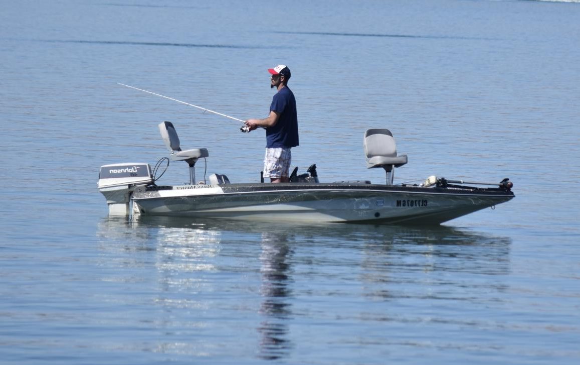 A man enjoys the reservoir, fishing from his boat.
