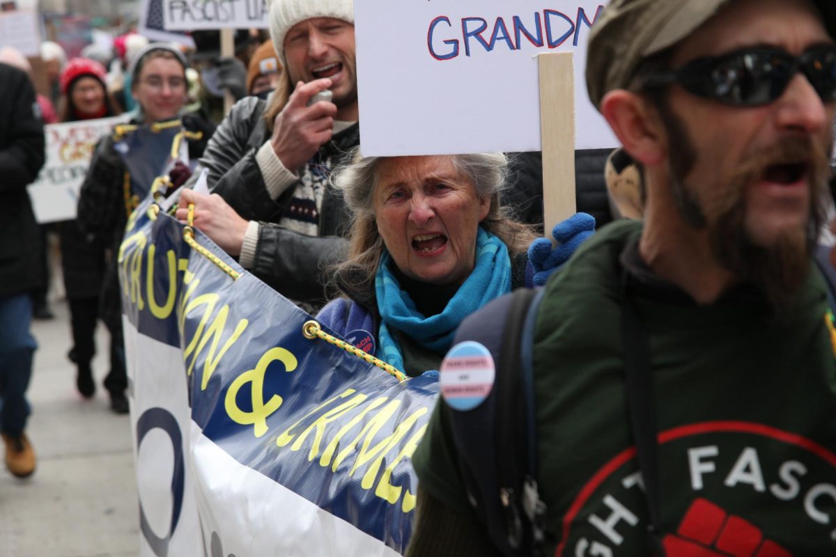 Framed by two other people carrying a banner, a marcher shouts out call and response chants to the crowd as they walk through the streets downtown Denver. The protest in the capital drew thousands of people, including Creek students to join the cheers.