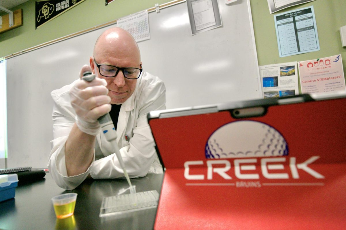 Biology teacher and boys golf coach Dustin Neel poses with a micropipette. He uses his expertise from his college experience and his PhD in performance psychology to teach  his students and his athletes better.