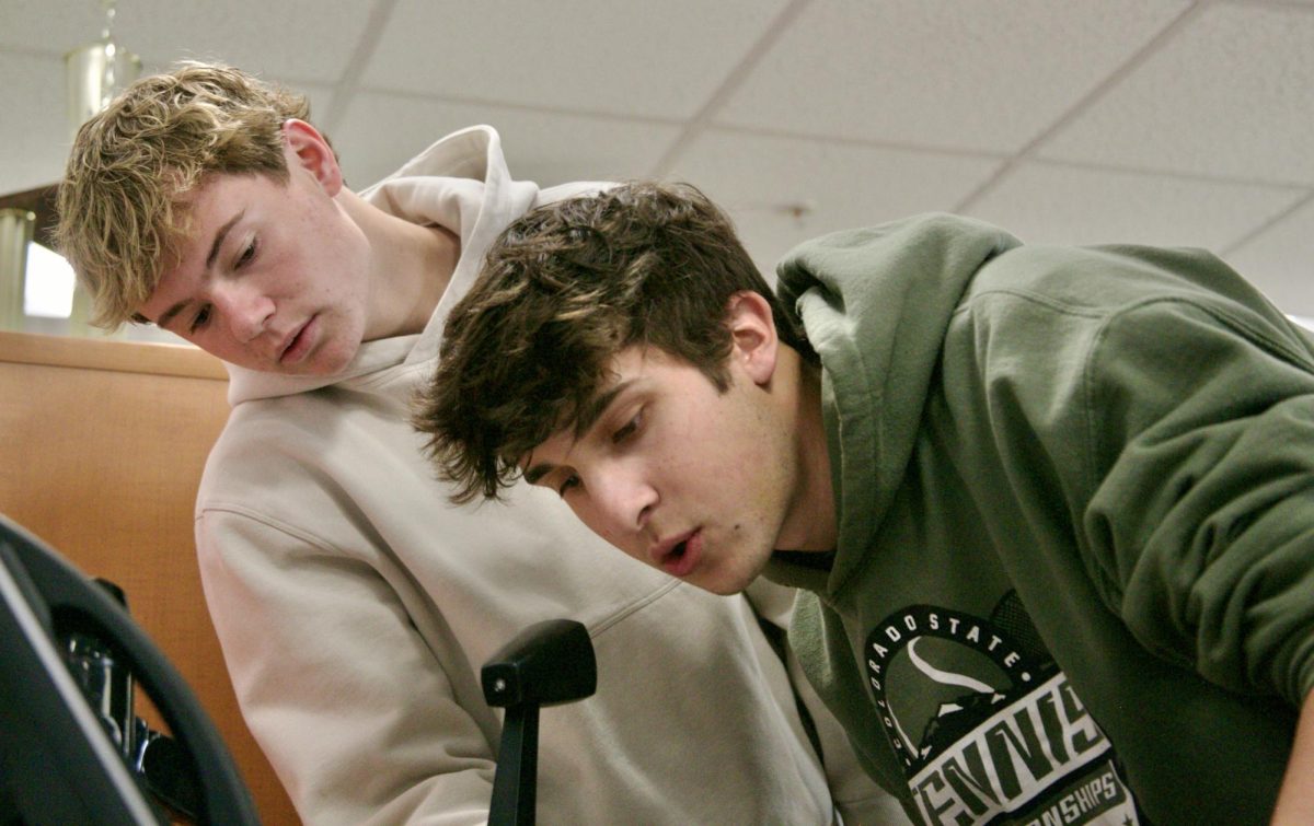 Seniors Dex Rhody (left) and Charlie Stern lean over the microphone, reading out sports announcements.